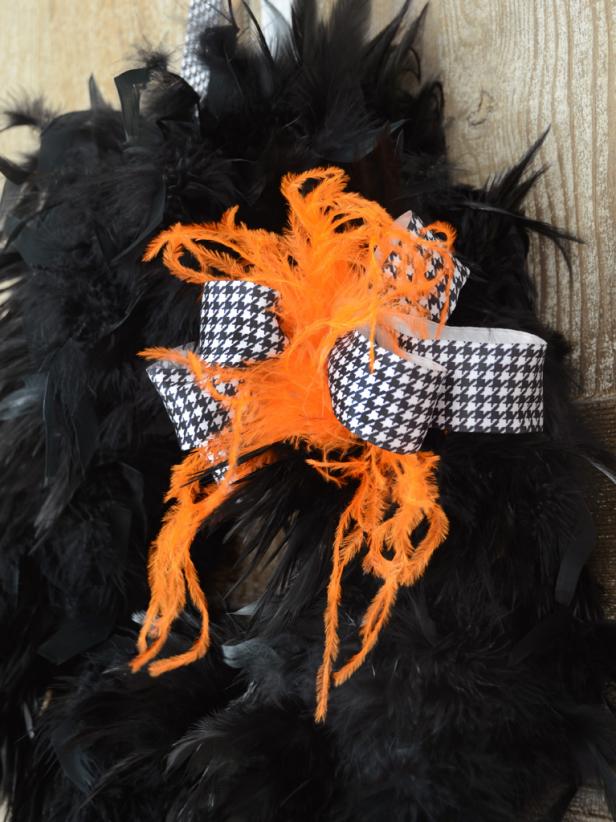An orange feather with a black and white ribbon is the perfect embellishment for a black feather Halloween wreath.