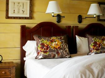 Yellow Bedroom With Wood Headboard, Floral Pillows and Botanical Prints