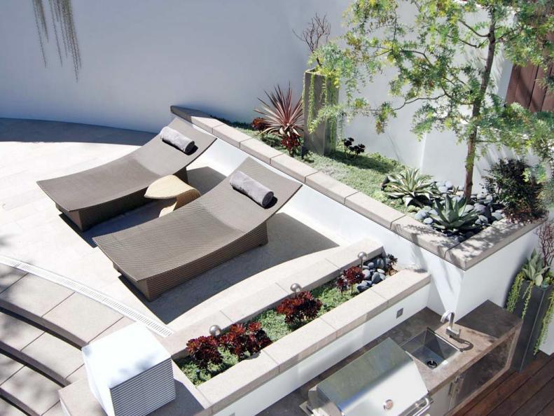 Concrete Patio With Brown Lounge Chairs and Two Small Plant Beds