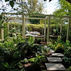 Shady Garden With Hanging Daybed and Paver Path