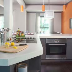 Modern Kitchen With Orange Accent Wall and Pendant Lights