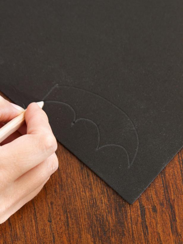 Use a pencil to draw the shape of a bat wing onto a sheet of thin black craft foam