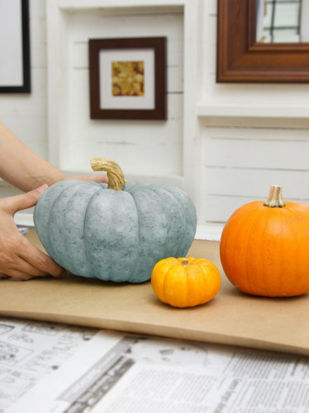 Put down a layer of newspaper topped with a sheet of craft paper to protect the work surface. Then select pumpkins of various sizes and colors, and decide which ones will receive which color glitter.