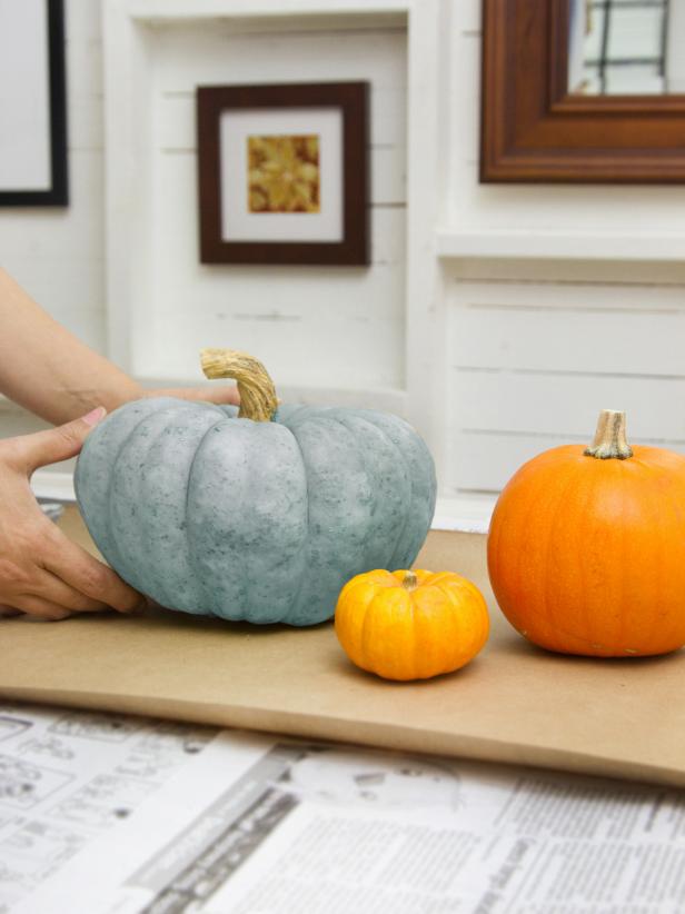 Put down a layer of newspaper topped with a sheet of craft paper to protect the work surface. Then select pumpkins of various sizes and colors, and decide which ones will receive which color glitter.