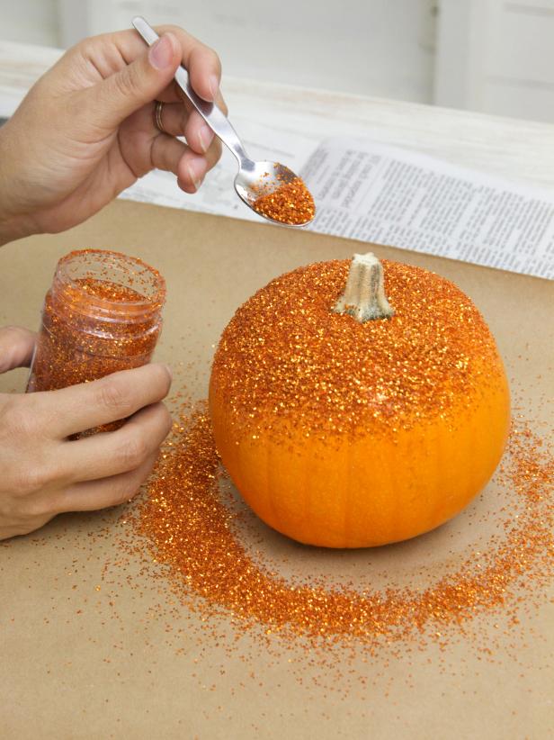 While the glue is still wet, use a spoon to sprinkle glitter over the sticky surface of the pumpkin. Allow to dry.