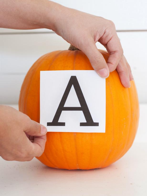 Measure the front side of your pumpkin to determine what size letter you'll need. Using your computer, select a font you like and print it out. Trim off most of the excess copy paper around the letter, then use painter's tape to attach the letter to the flattest side of the pumpkin.