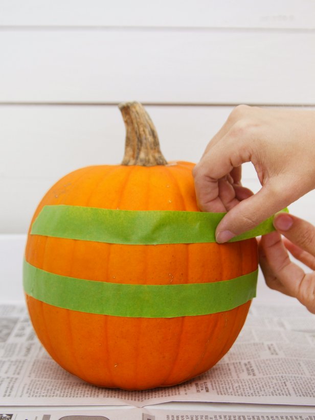Attach a piece of painter's tape around the center of the pumpkin. Apply another row of painter's tape approximately 2 inches above the first piece of painter's tape.