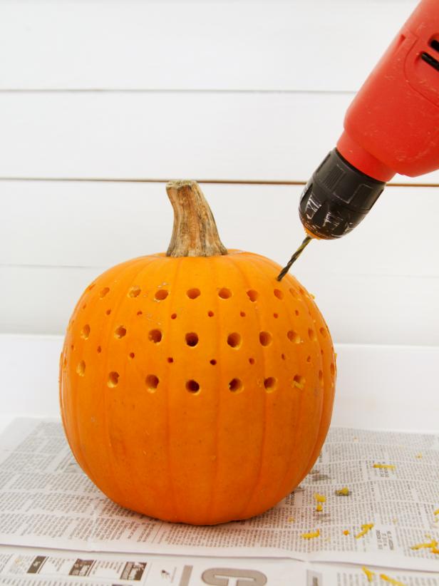 After drilling the large holes, replace the large drill bit with a much smaller one and drill smaller holes in between and above each of the large ones, all the way around the pumpkin.
