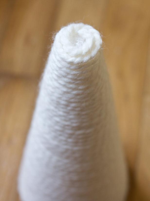 Once yarn has been wrapped tightly and you've reached the top, cut off the end of the yarn and secure it to the top of the cone with a dab of hot glue.