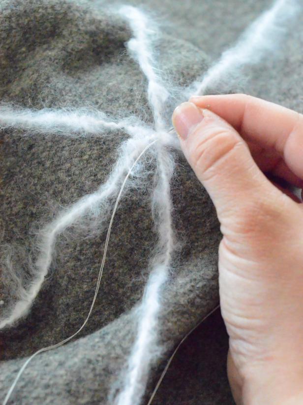 Starting at the outside and working toward the middle, create a web by tacking yarn into place at each intersection. Continue all the way to center of web, and trim excess yarn. Tack down any yarn pieces that are not lying flat against the wool.