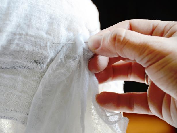 Using an all-purpose sewing needle threaded with white cotton thread, hand-stitch cheesecloth to slipcover in two or three places per strip (Image 3). Trim all excess threads.