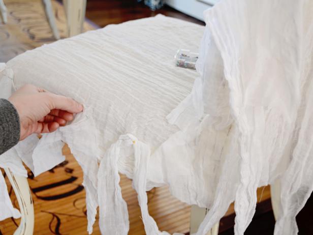 Drape strips of cheesecloth randomly over back and sides of slipcover and pin into place.