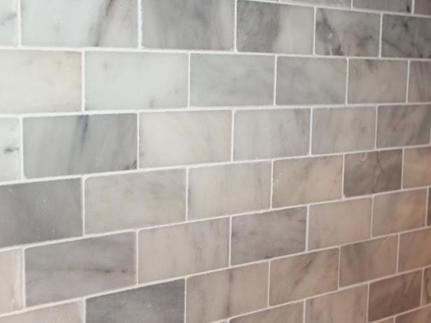 Using circular motions, clean the surface with a damp grout sponge, frequently rinsing and wringing it out in the sink. Continue cleaning grout till there is no visible haze.