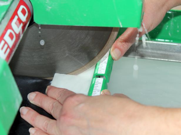 Turn on the wet tile saw, allowing water to coat the blade. Position tile so the blade will hit on your marked line and slowly move tile through the saw.