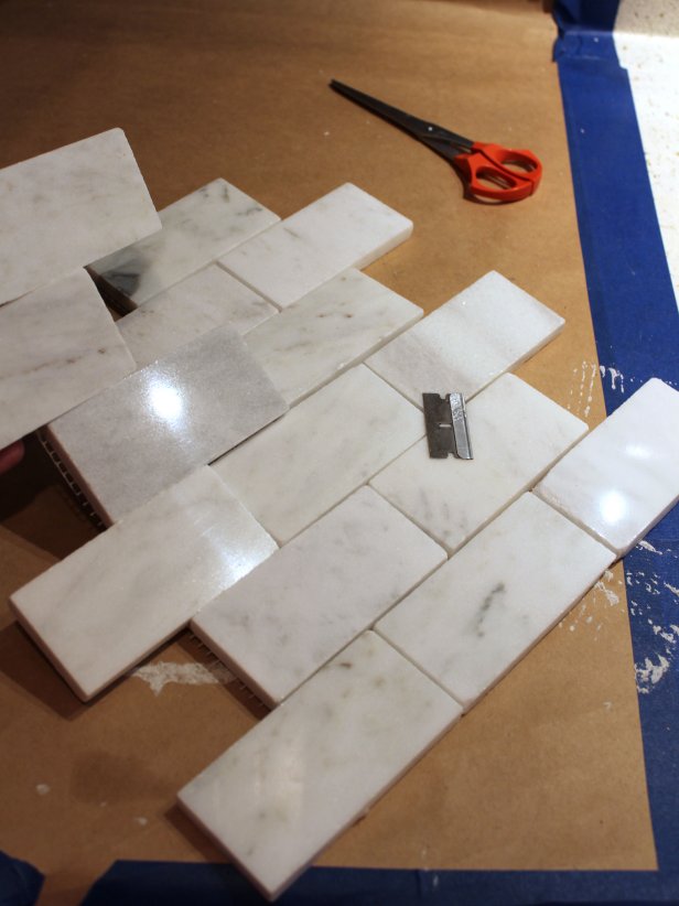 Applying full sheets of mesh-backed tile to the wall can be tricky around outlets or other obstacles, so it's easiest to cut apart and set individual tiles around these. Using a razor blade or scissors, cut tiles away from the mesh backing.