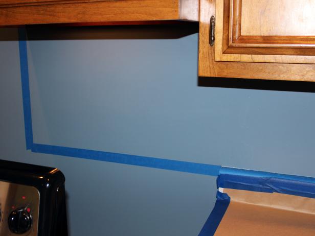 Use a spirit level to draw straight lines delineating areas, like behind the stove, where tile will continue beyond the countertop. Cover this line with painter's tape.