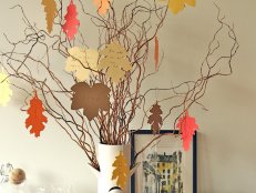 Multicolored Paper Leaves Hang on Spindly Branches in White Vase