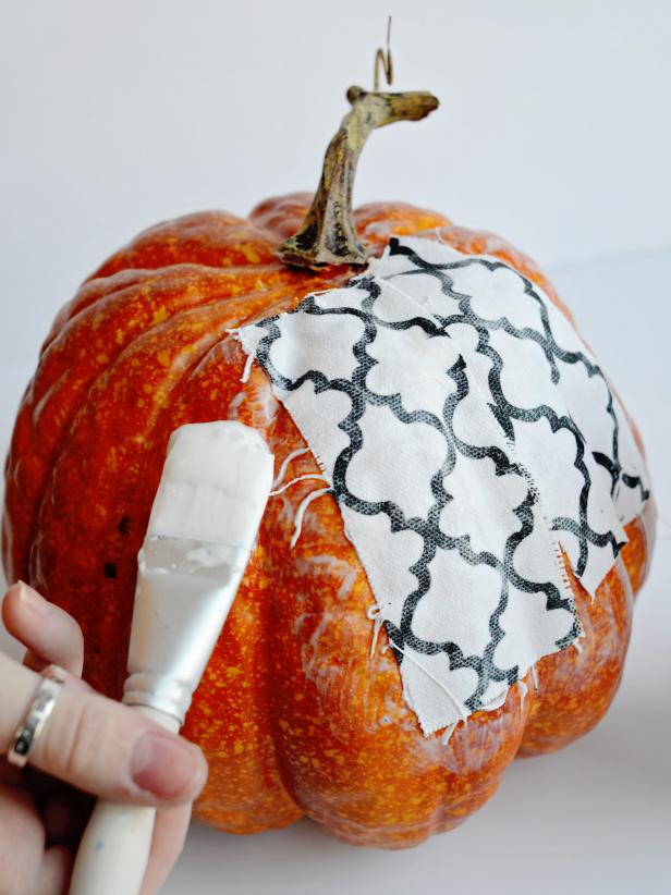 Place pumpkin on a piece of wax paper, parchment paper or tin foil to protect work surface from glue. Using one-inch artist brush, apply a small amount of decoupage medium to surface of artificial pumpkin. Press a strip of fabric into wet glue. Immediately brush over fabric with a generous amount of decoupage medium until fabric is fully saturated. Brush more medium on pumpkin next to fabric strip that was just glued.