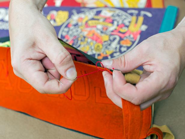 Starting from the top thick end of each pair of overlapping pennants, loop threaded needle in and out, creating a whip-stitch. Continue stitching until you are four inches away from the bottom tip, then create a knot and cut thread.