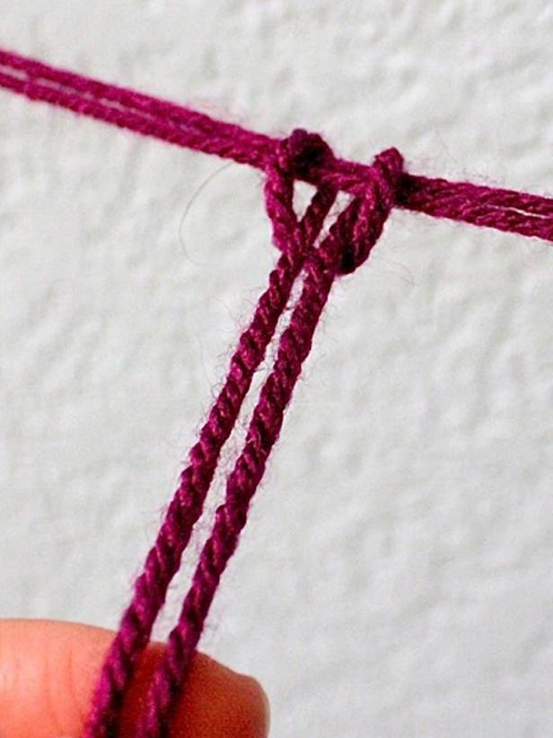 Cut a very long strand of yarn for each section — longer than you think you'll need. Fold it in half and start the ring with a simple loop knot. Then take the yarn around to each arm and simply loop it around. You don't need to tie knots — this is fast and easy. Don't try to be accurate and precise. It's better to look wonky here and there. When you get back around to beginning of the ring, tie the end with a knot, cut off the excess and start over on the next ring.