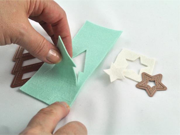 In step 4, create a Christmas tree and star out of felt using tree and star dies or craft scissors, cutting an aqua felt tree and white star.