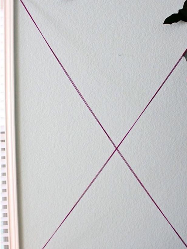 Use double strands of yarn, and tape the ends to the wall and cabinet with simple Scotch tape. Make an X.
