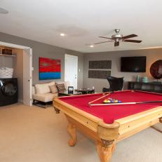Transitional Game Room With Red Pool Table and Tuck-Away Laundry Room