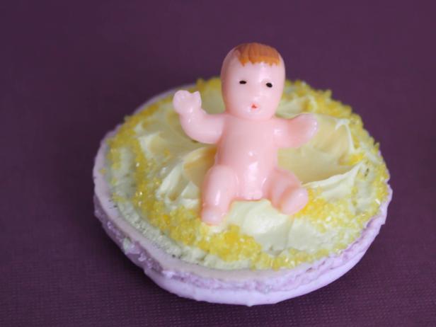 Small plastic baby in the middle of a macaron shell. 