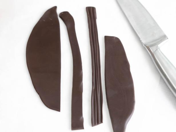 Cut long strips of chocolate fondant in matching lengths and striate with a toothpick or the back of a knife to begin forming the edge of the roof.