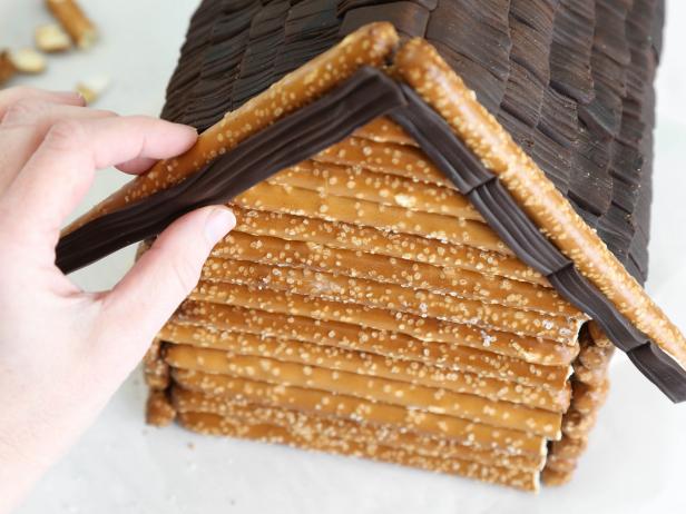 Adhere chocolate fondant pieces with dabs of royal icing just underneath the pretzel pieces on your gingerbread house. Use the back of a knife to make lines in the fondant mimicking planks/boards.