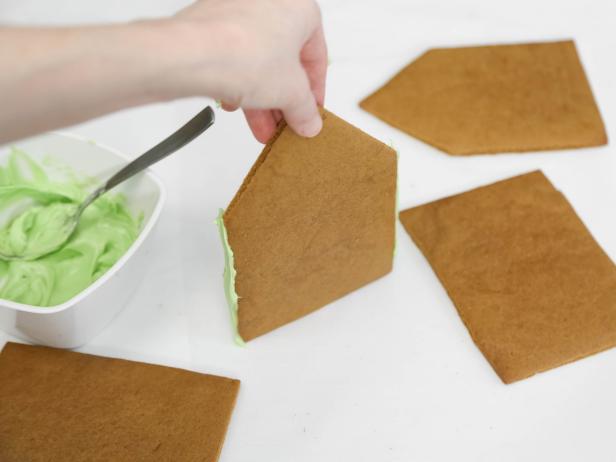 Coat the short sides of a front/back gingerbread piece with candy melts using a spoon.