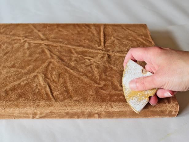 Starting with coarse-grit sandpaper (and working your way down to medium- then fine-grit), sand the leather, concentrating on any wrinkles or raised areas and the edges of the spine. Tip: Just like distressing furniture, the key is to sand the areas that would naturally see the most wear and tear over time.