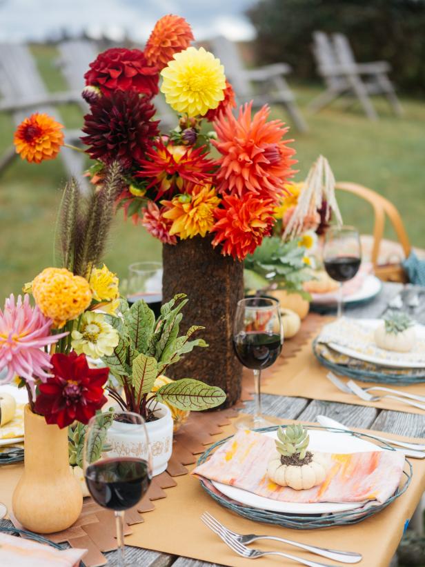 An outdoor table is topped by a gorgeous fall centerpiece and table setting.