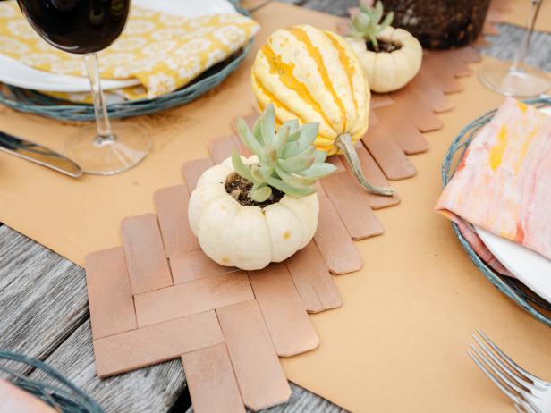 Paint-stirring sticks find new life as an upcycled herringbone table runner on this rustic fall tablescape, complete with succulents in miniature gourd planters.