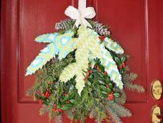 Instead of a traditional evergreen Christmas wreath, dress up your front door with a holiday swag made from fresh greenery, fabric branches and glittering pinecones.