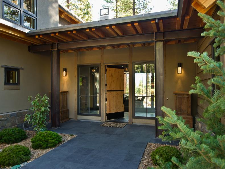 Rustic Home Entrance With Industrial Columns and Wood Front Door