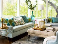 The soft shades of blue, green and beige used throughout this living room blend seamlessly with the serene outside view. Your eye easily takes in both the interior design choices and the beauty beyond all the windows because they don't compete.