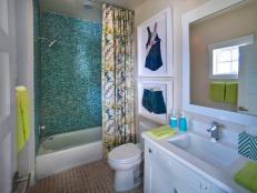 The shower stall, clad in sea-inspired glass tile, lends drama to a space defined by tropical-print fabrics and unique artwork.