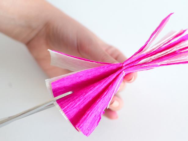 Use scissors to cut along each of the paper's folds being careful not to cut the center's string.