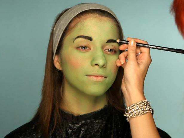 To turn your tween into a hip Frankenstein for Halloween, begin with a green cream makeup base. Cover entire face using a sponge. Using a fluffy blending brush and a light green eye shadow, cover the face everywhere the green cream makeup was applied. Add a touch of pink blush to apples of cheeks. Define eyebrows with brown or gray eyebrow pencil. Cover eyelids with a purple or mauve eyeshadow and blend up to crease. Use a slightly lighter shade at the halfway point and blend the colors together. For older girls who are comfortable wearing eye makeup, add black liner and mascara to top and bottom lashes to define them and make the eyes appear larger. Add stitch lines and bolts.