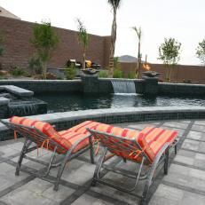 Gray Concrete and Tile Pool With Striped Lounge Chairs