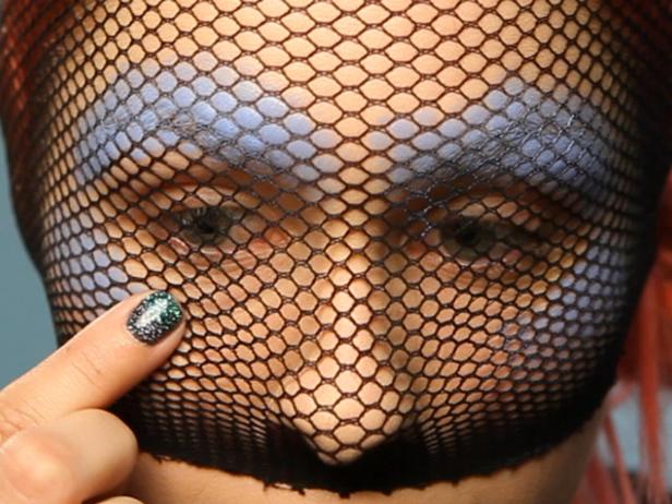 Cut one leg off a pair of regular fishnet stockings, then cut off the foot end to make it into a tube. Gently stretch the widest part of the hose over your face. Using a brush, sponge or your finger, dab the blue creme foundation around eyes, brows and cheekbones, making sure to keep the fishnet from shifting as you work.