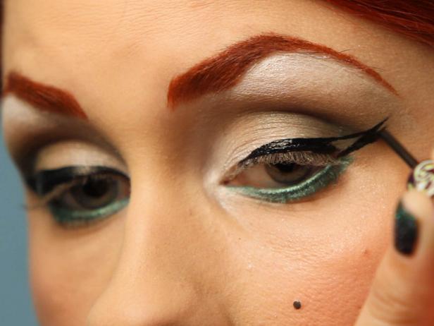 Use black liquid eyeliner to create a thick cat eye. Start at the center and wing out, then go back to the inner corners and connect the line all the way across your lid.