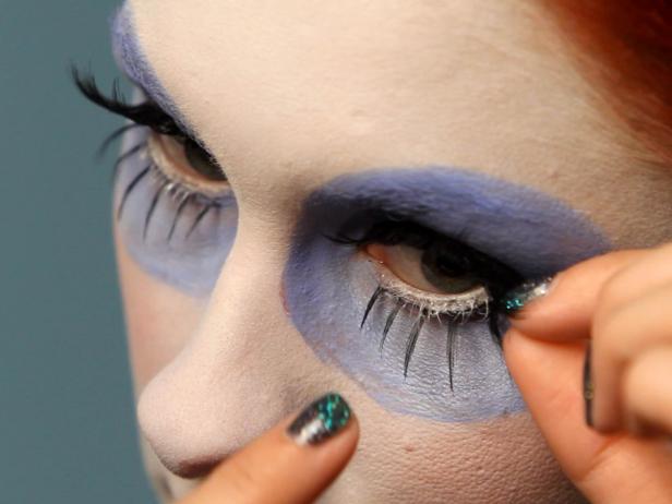 Apply spidery false lashes to the top and a pair of shorter lashes underneath eyes where black eyeliner was painted.