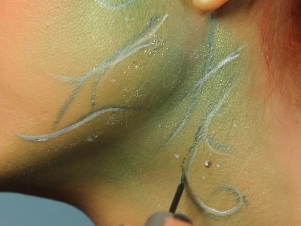 Add some subtle dots with the white liquid liner for texture, then use green glitter liner to trace around the vines.
