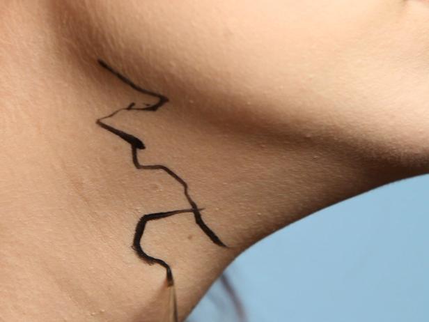 Take a liquid eyeliner with a very thin tip and draw on squiggly cracks and veins coming down from the hairline at the forehead, down into the eyebrow, out from under one eye and at the sides of the cheeks. Add more down the chin and neck, on your clavicle and anywhere skin is showing.