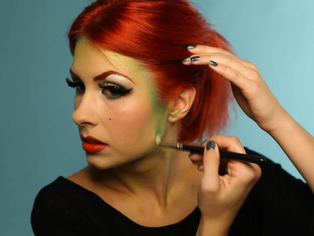 Begin to blend green eyeshadow around the edges of your face and in your cheek contour. Blend 2 to 3 shades of green in a gradient starting at your hairline, and working outward. Choose a deep forest green shade, a Kelly green and a lime shade; at least one of your shadows should have shimmer in it.