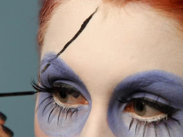 Using a black liquid eyeliner or black cream color, paint one line across forehead down into one of the circles around the eyes and out the other side.
