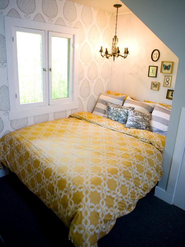 Bedroom With Patterned Wallpaper, Yellow Bedding and Gold Chandelier