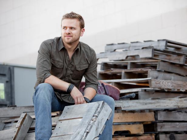 Licensed Contractor and host of Bath Crashers, Matt Muenster, sits posing on a stack of wooden pallets